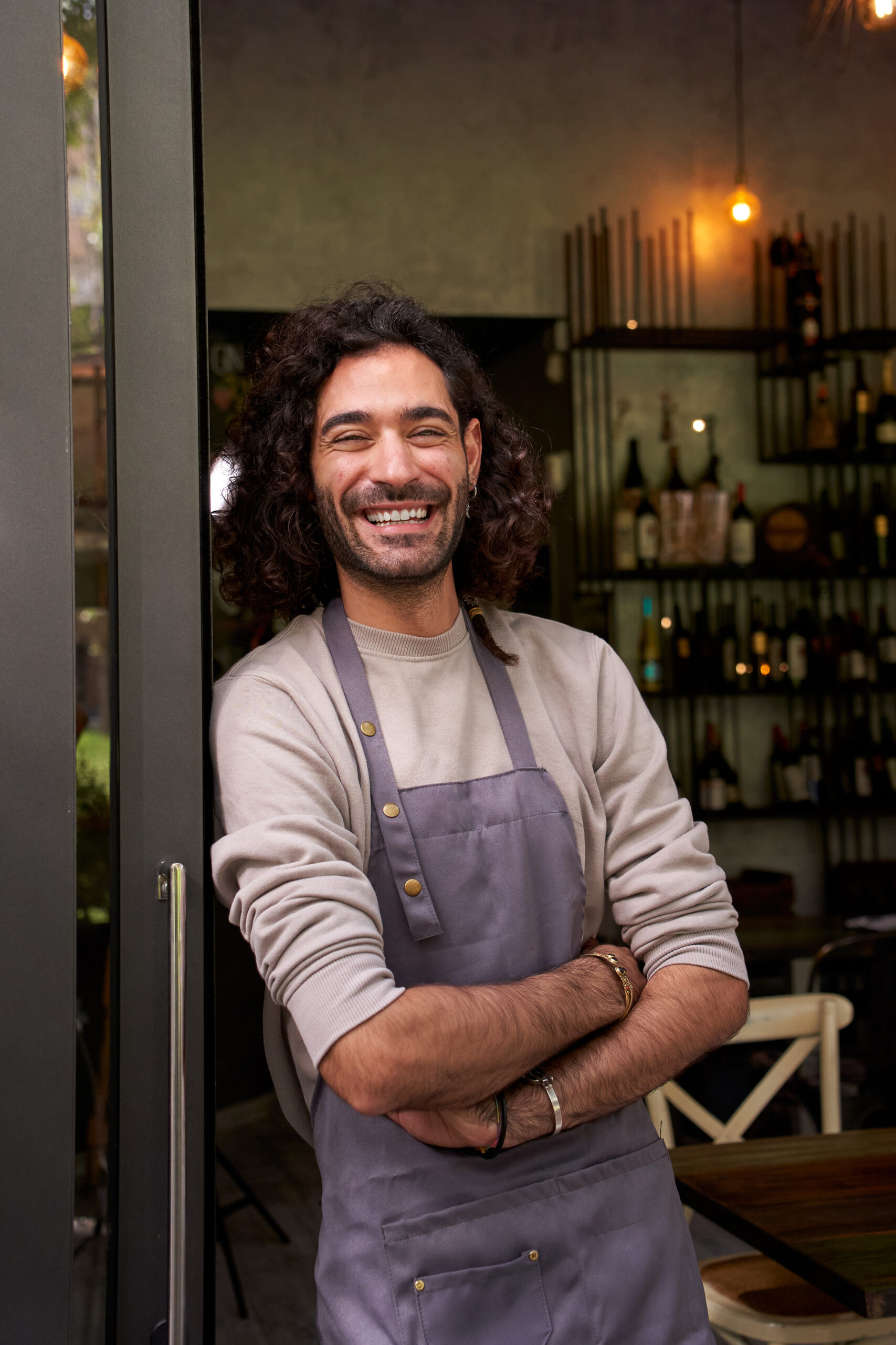 Vertical portrait young adult local small business owner looking camera. Cheerful bar worker smiles.